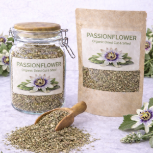 Bulk dried passionflower herb in a glass jar and kraft resealable pouch with wooden scoop spilling loose cut leaves on marble surface, fresh purple and white passionflower blossoms arranged around packaging.