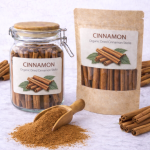 Organic dried cinnamon sticks in a glass jar and kraft pouch with wooden scoop of ground cinnamon on marble surface, whole cinnamon sticks arranged around packaging.