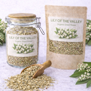 Dried Lily of the Valley flowers in a glass jar and kraft resealable pouch with wooden scoop spilling loose dried blossoms on marble surface, fresh white bell-shaped lily of the valley blooms and green leaves arranged around packaging.